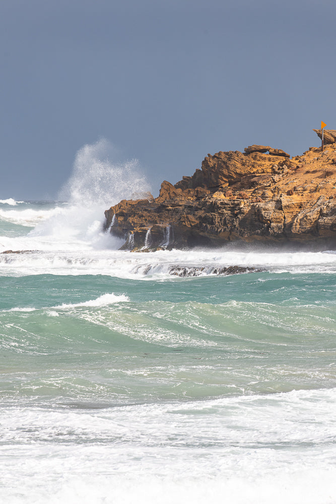 Waves crashing against orange rugged cliffs in Warrnambool