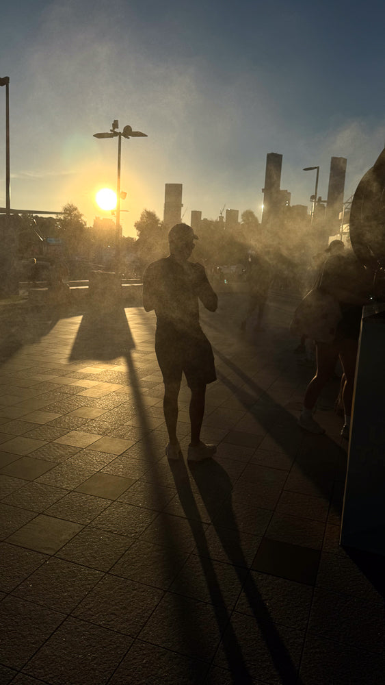 Man walks through mist at sunset with city skyline.