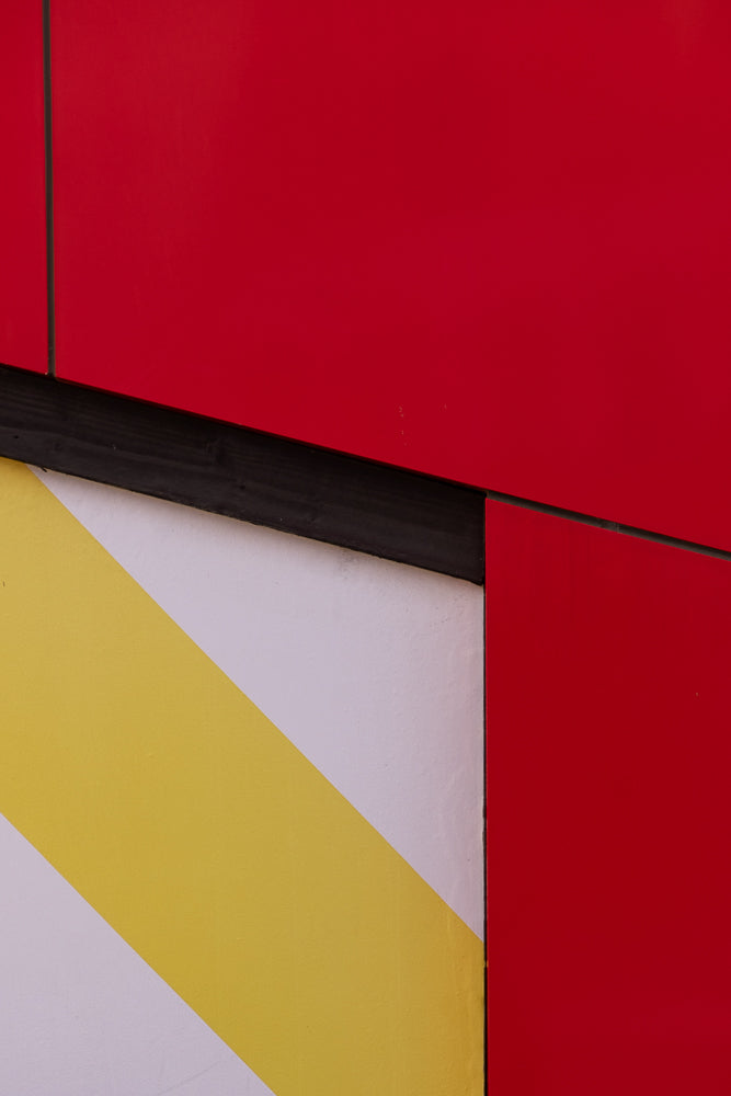 Abstract image with bold red panels and a diagonal stripe pattern of yellow and white, separated by a dark horizontal line.