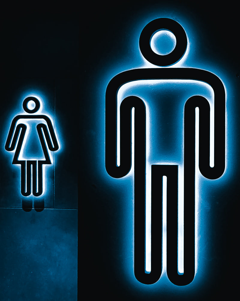 A modern, stylized neon sign for a restroom, featuring a glowing blue outline of a male figure on the right and a female figure on the left.