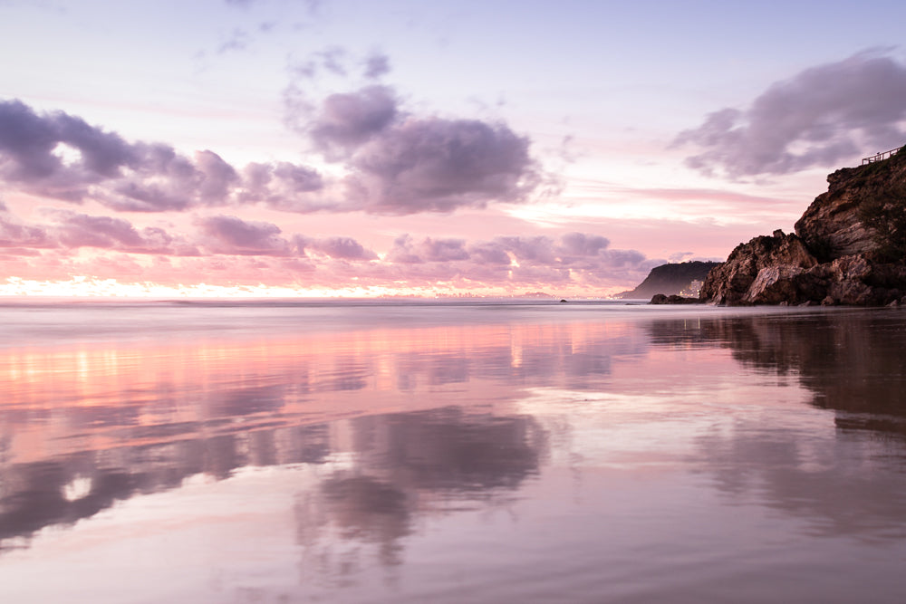 Pastel pink sunset at beach reflecting off wet sand, with Miami Beach Point at Gold Coast