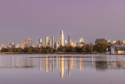 Melbourne skyline reflected on Albert Park Lake with purple sunrise