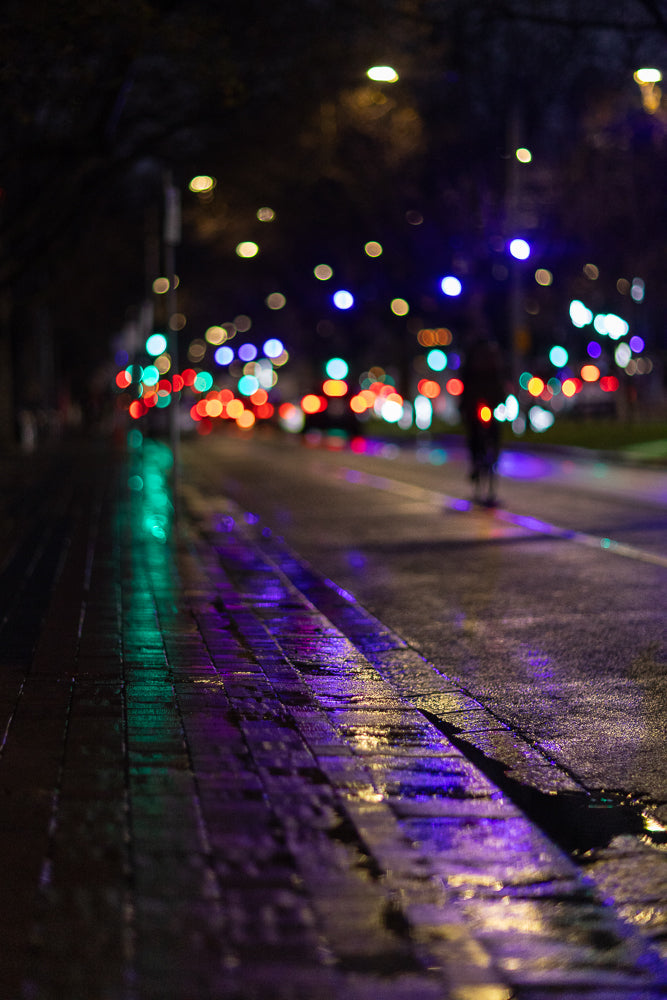 Rainy night street with colorful bokeh lights and reflections.