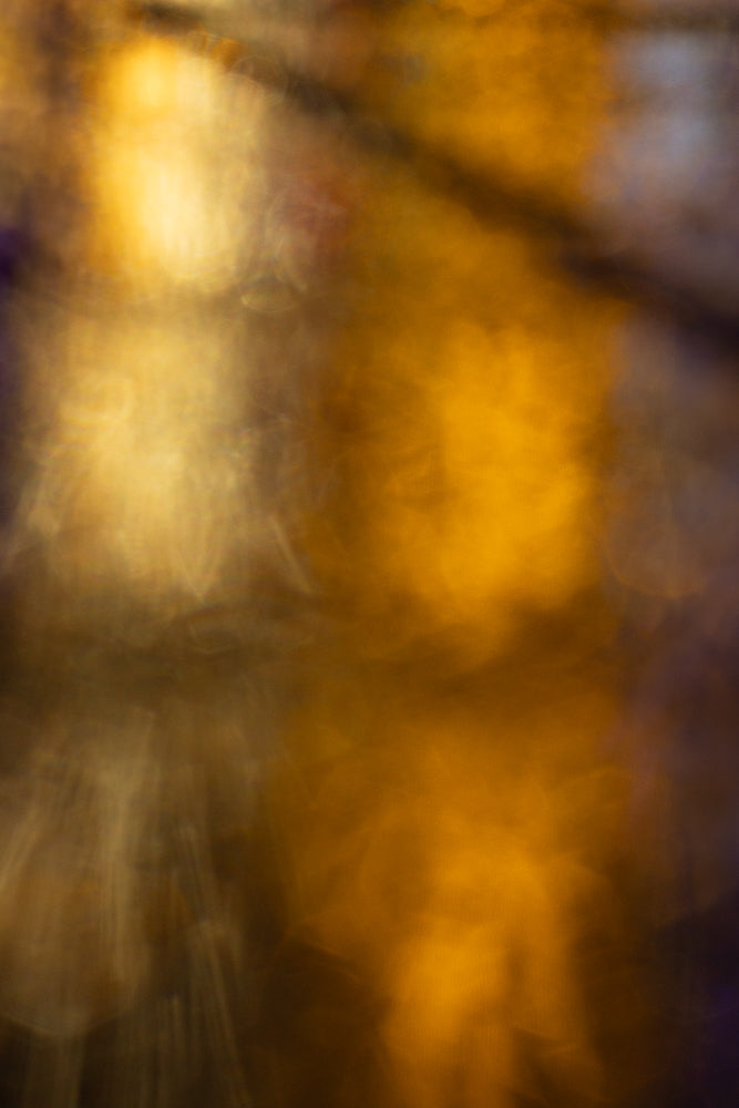 An abstract background with soft, blurred golden and brown tones, suggesting a warm, ethereal glow. The lighting creates a dreamy, out-of-focus effect with subtle variations in color and light intensity.