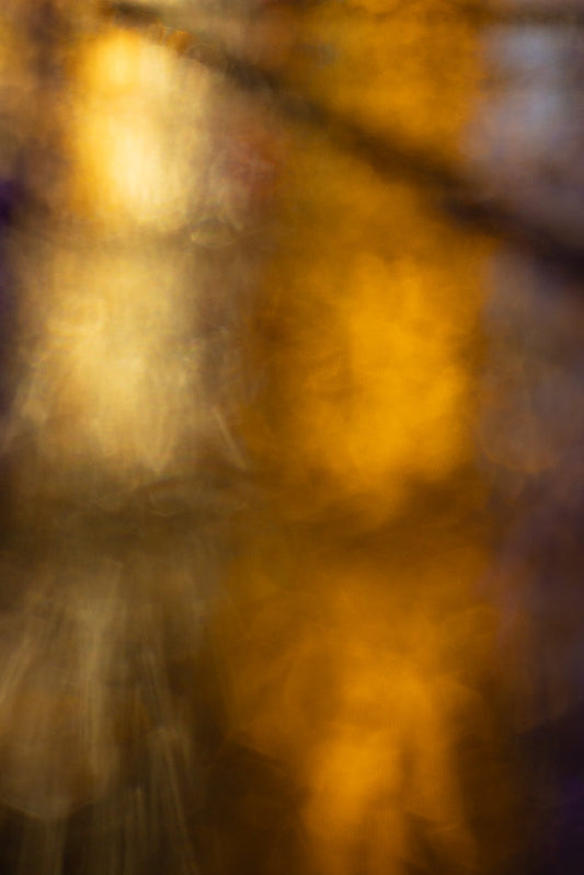 An abstract background with soft, blurred golden and brown tones, suggesting a warm, ethereal glow. The lighting creates a dreamy, out-of-focus effect with subtle variations in color and light intensity.