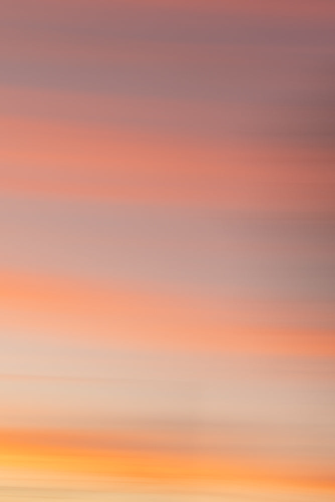 Abstract background of soft, horizontal bands of color transitioning from pale orange and yellow at the bottom to pink and muted purple at the top, evoking a serene sunset or sunrise.
