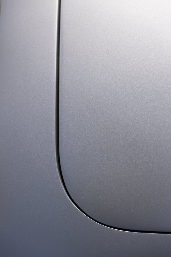 Close-up of a metallic gray car door with a subtle curve and a thin black seam.