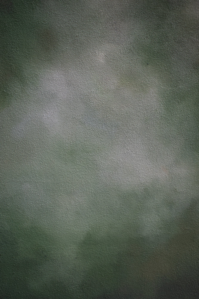 A textured, dark green background with a subtle gradient, lighter in the center and darker towards the edges. The surface appears to be a matte material, possibly fabric or painted wall.