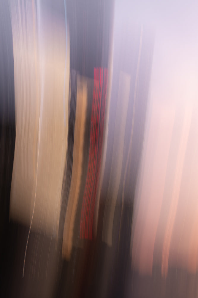 Abstract image with vertical streaks of color. A central vertical band of red stripes is flanked by bands of beige, gray, and soft pinkish-purple. The streaks suggest movement or light trails.