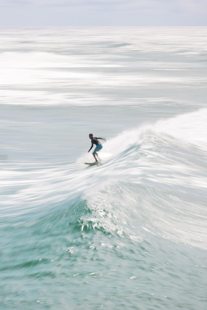 Motion blur ICU of Surfer riding turquoise ocean wave in summer
