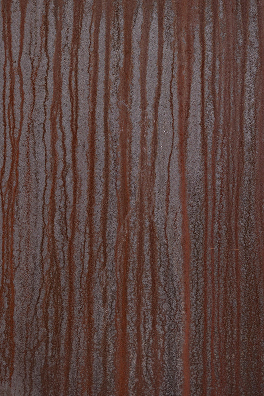 A close-up, full-frame shot of weathered, rusty metal with vertical streaks of darker rust running down the surface. The texture is rough and pitted, with a mottled pattern of brown and gray hues.
