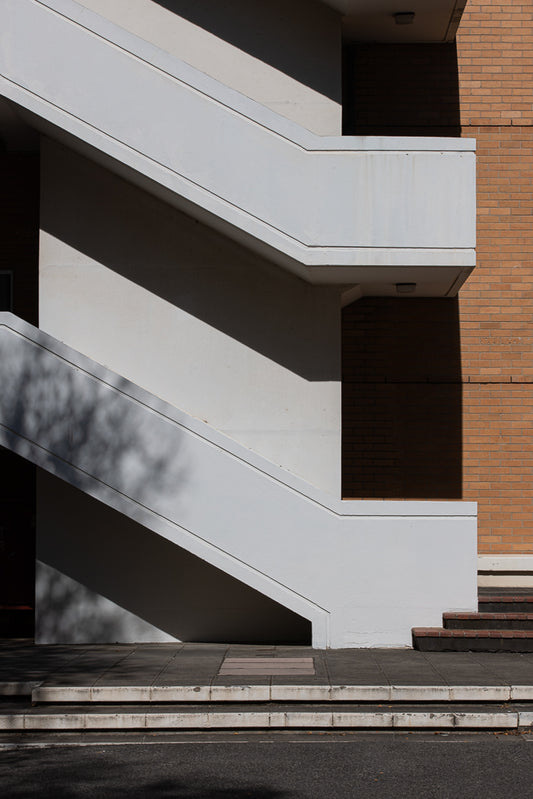 White retro staircase casting shadows on a blonde brick building