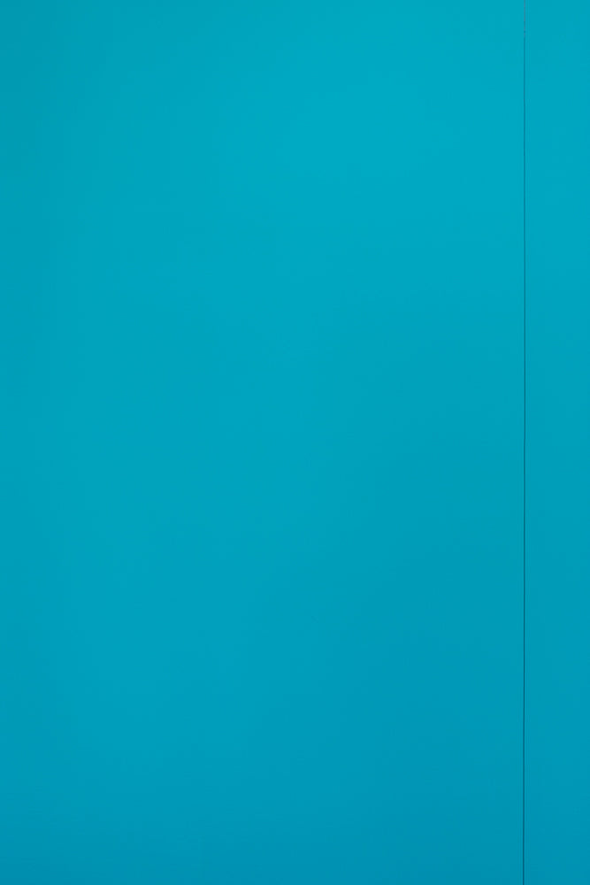 A solid, bright teal blue background with a thin, vertical dark grey line on the right side of the frame.