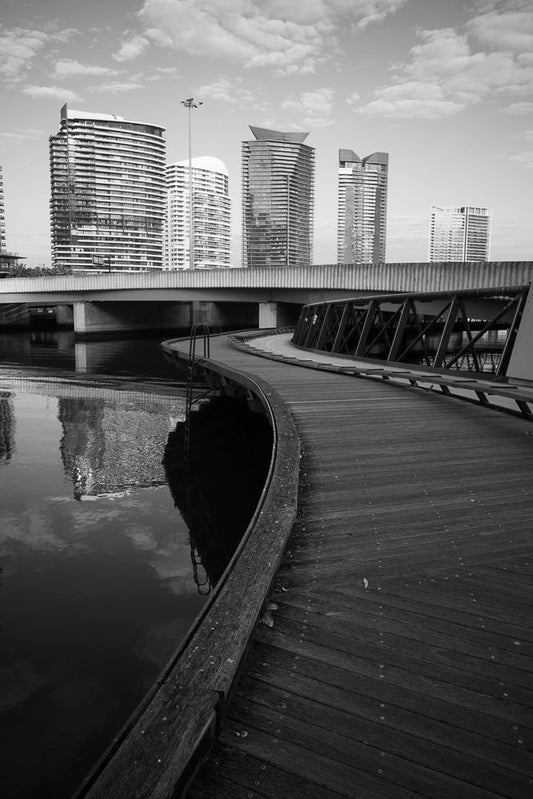 Curved pier leading to Melbourne skyline in black and white