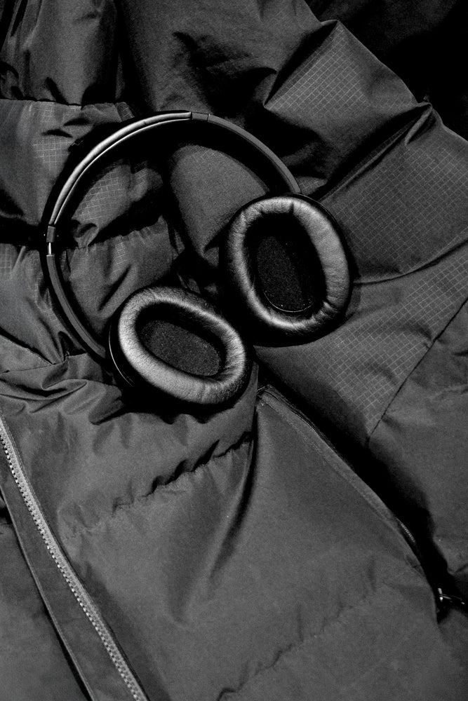 A pair of black headphones rests on a dark, wrinkled jacket