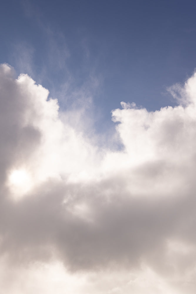 The sun shines through a gap in the clouds, illuminating the sky with a soft glow.