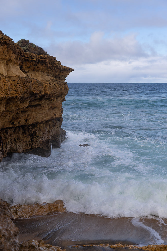 Waves crash against the edge of a coastal cliff in Torquay