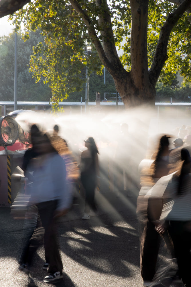 Urban crowd cooling down with misting fans