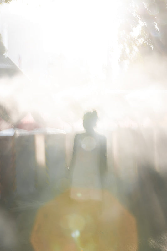 Woman silhouette walking into bright light with lens flares