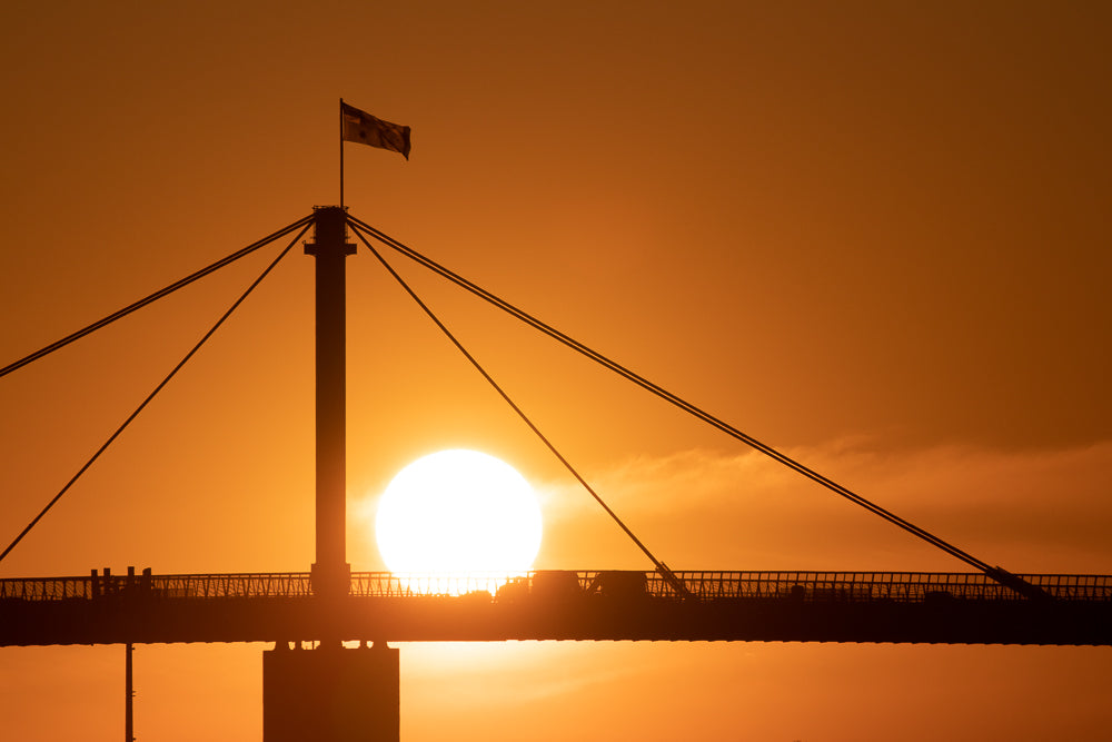 Silhouette of a bridge with a bright orange sunset