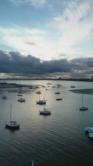 Aerial fly over sailboats moored in a tranquil St Kilda marina at dusk with calm glassy water in Port Phillip Bay Melbourne
