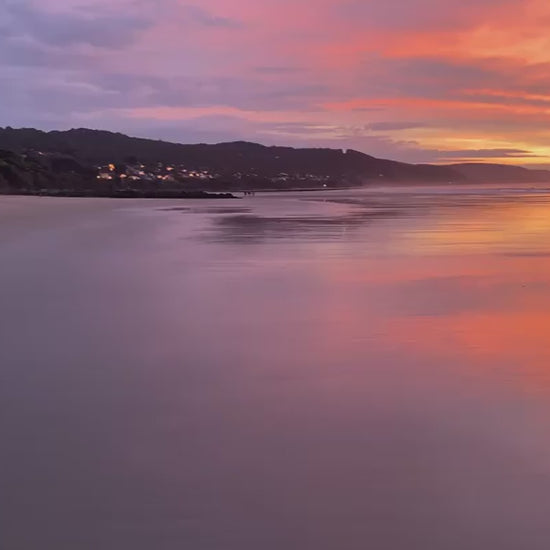 Breathtaking ocean sunset with a vibrant orange and purple sky. Dramatic clouds and colorful light reflecting on the wet sand of a tranquil beach