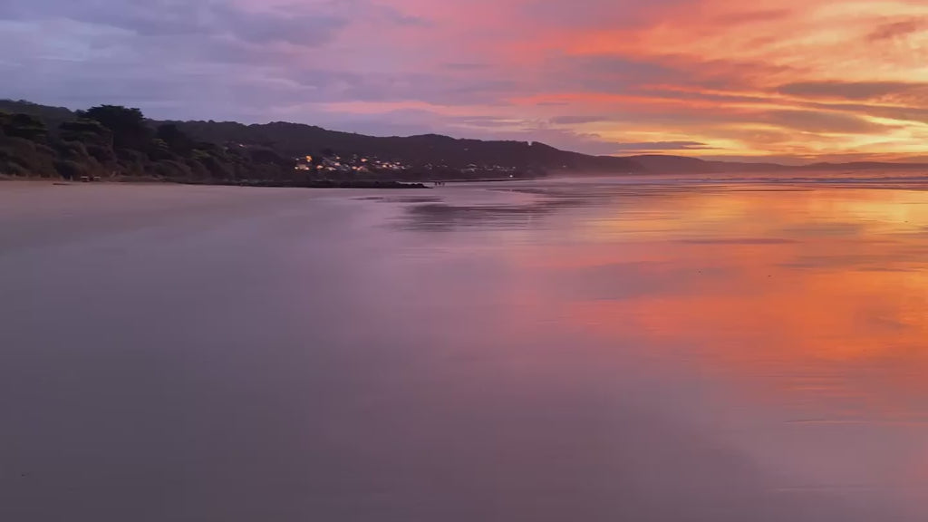 Breathtaking ocean sunset with a vibrant orange and purple sky. Dramatic clouds and colorful light reflecting on the wet sand of a tranquil beach