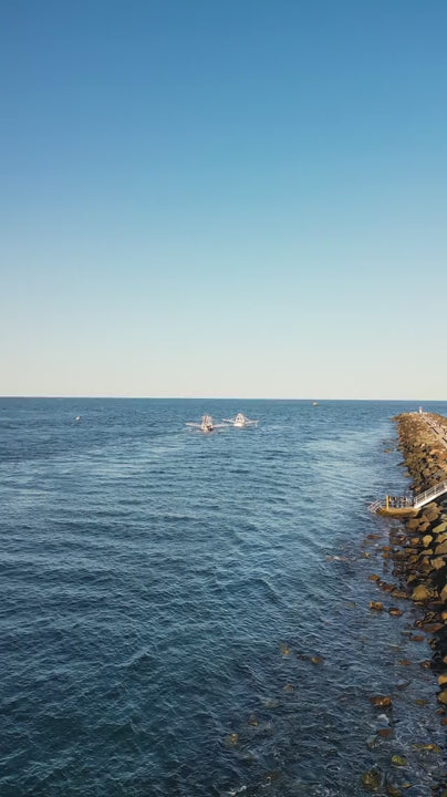 Fishing trawlers near a rock wall in the ocean
