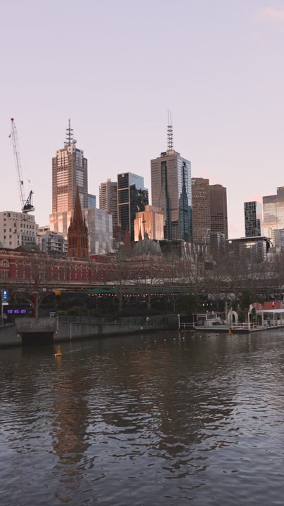 Melbourne city skyline reflecting on yarra river at dusk, with flinders street station and st paul's cathedral