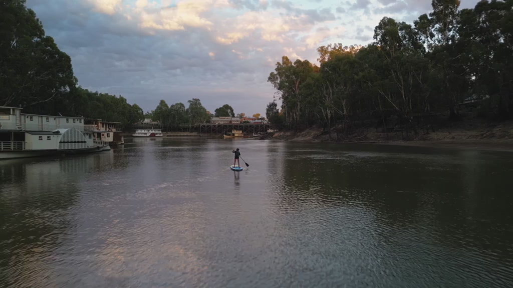 Beautiful drone shot across Murray River from Paddleboarder to Echuca Discover Centre at Sunset. High quality 4k footage