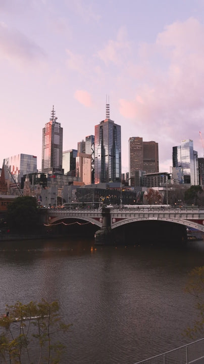 Rowers on the Yarra River at sunset with Melbourne skyline reflecting the pastel pink and purple sky