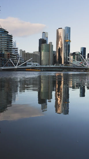 Melbourne city skyline reflecting perfectly on yarra river at dusk, with subtle ripples disturbing the mirror image
