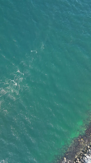 White sailboat gliding smoothly over rippled turquoise ocean waters, capturing nautical freedom and serene maritime adventure from aerial perspective