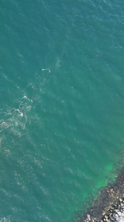 White sailboat gliding smoothly over rippled turquoise ocean waters, capturing nautical freedom and serene maritime adventure from aerial perspective