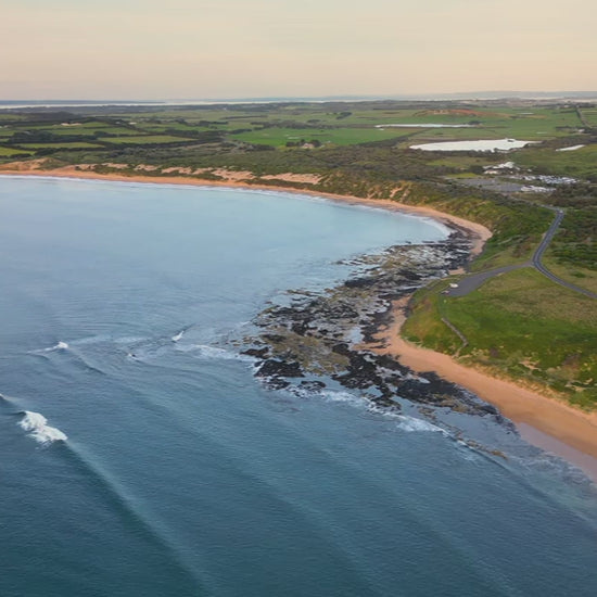 Aerial high fly over ocean to land, showcasing a scenic coastline