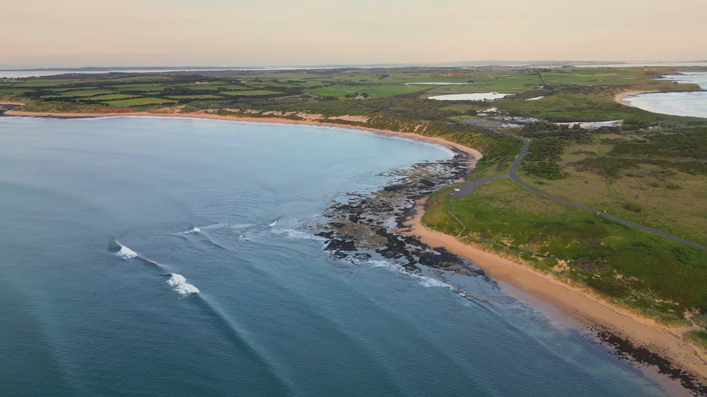 Aerial high fly over ocean to land, showcasing a scenic coastline