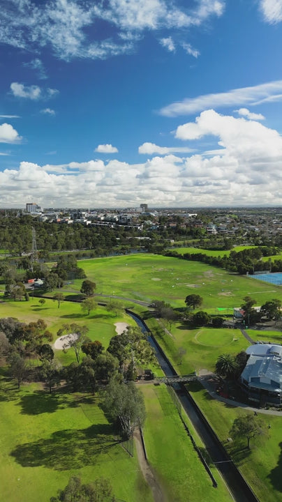 Aerial of Melbourne outdoor community sporting fields of tennis courts, ovals and parklands under blue sky- fly over