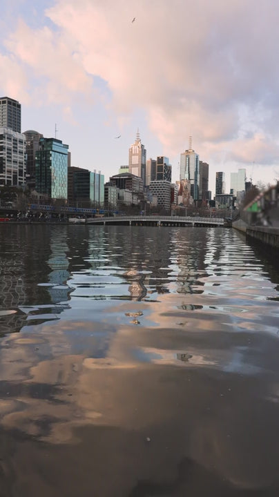 Pink and orange pastel sunset clouds reflecting on Yarra River with Melbourne city skyline in the background