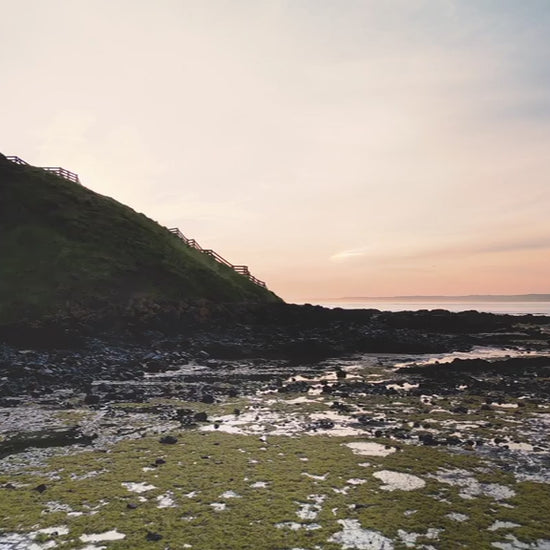 Aerial view of a cliff and ocean at sunrise, fly over hill
