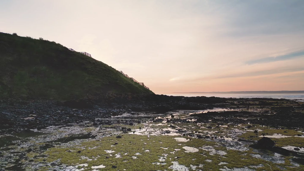 Aerial view of a cliff and ocean at sunrise, fly over hill