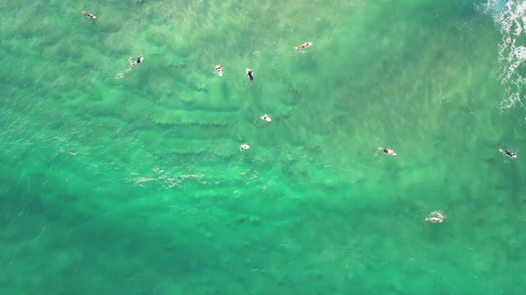 Top-down aerial view of surfers catching a wave on the Gold Coast